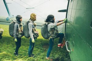 Excited skydivers climb onto a plane, preparing for an exhilarating jump. Perfect for adventure themes.